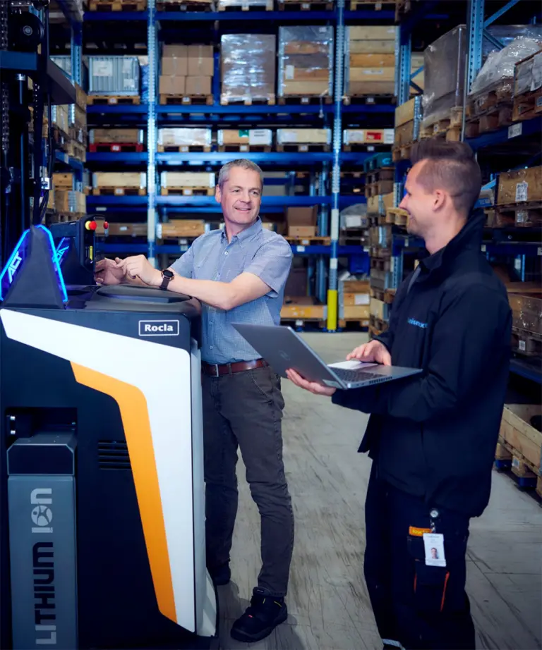 Konsulenter fra Logisnext Denmark konfigurerer Rocla AGV-truck med bærbar computer i lager